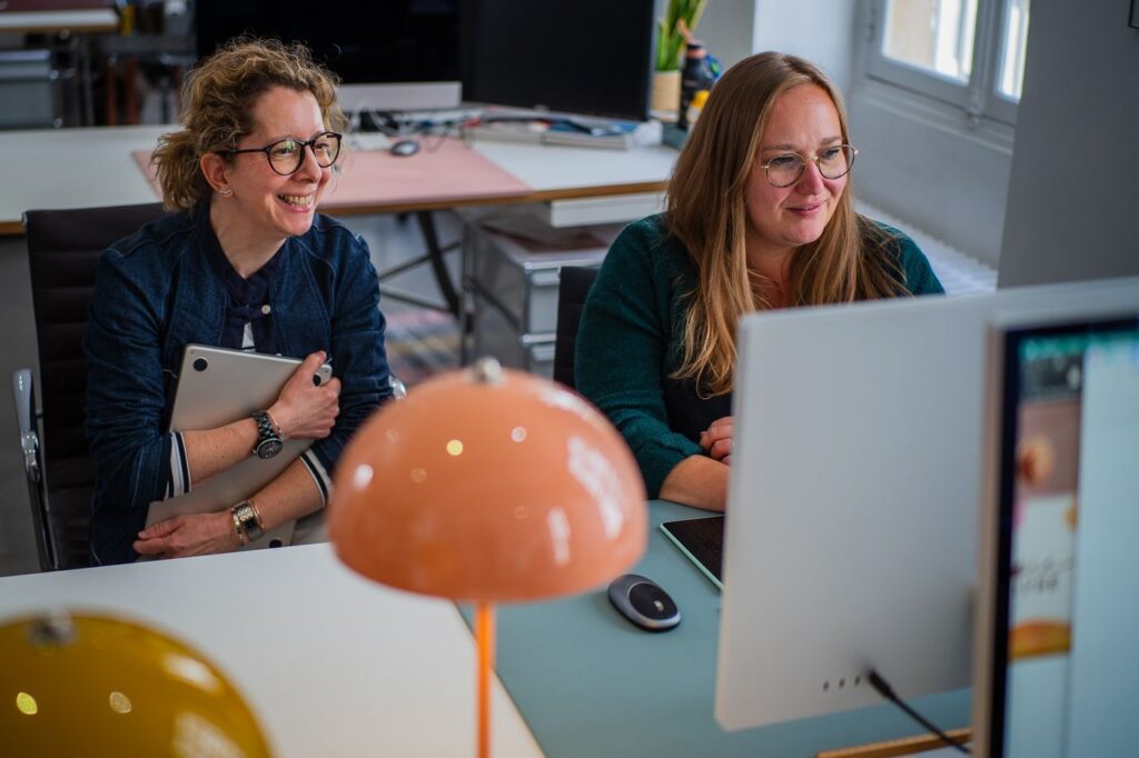 Two smiling team members at their workstations