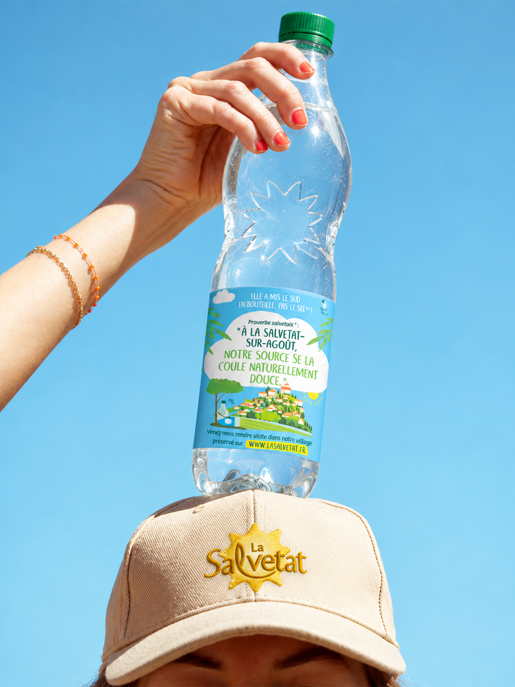 Bouteille La Salvetat tenue au-dessus d'une casquette brodée du logo de la marque