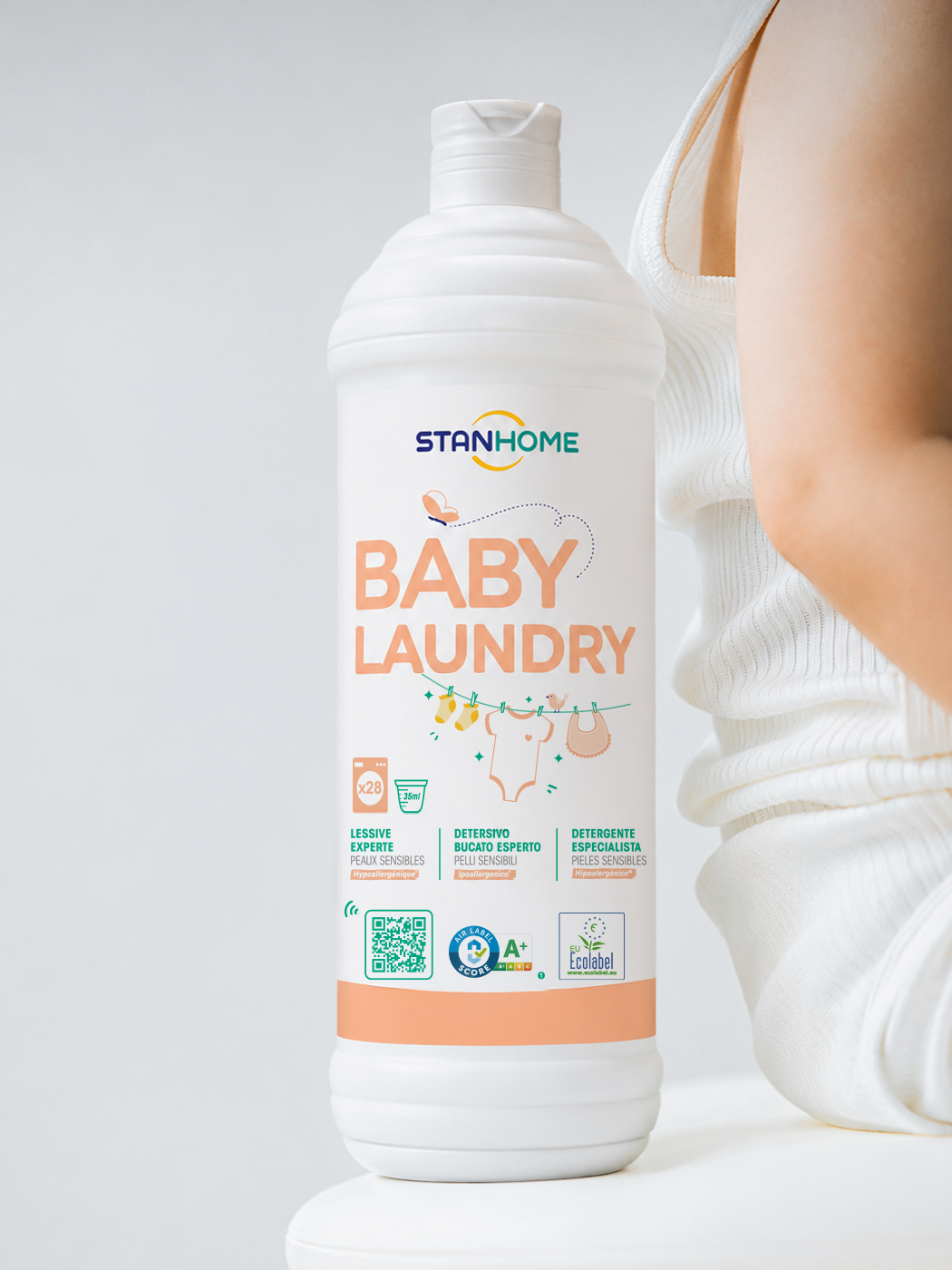 Flacon Stanhome Baby Laundry devant un bébé en body blanc