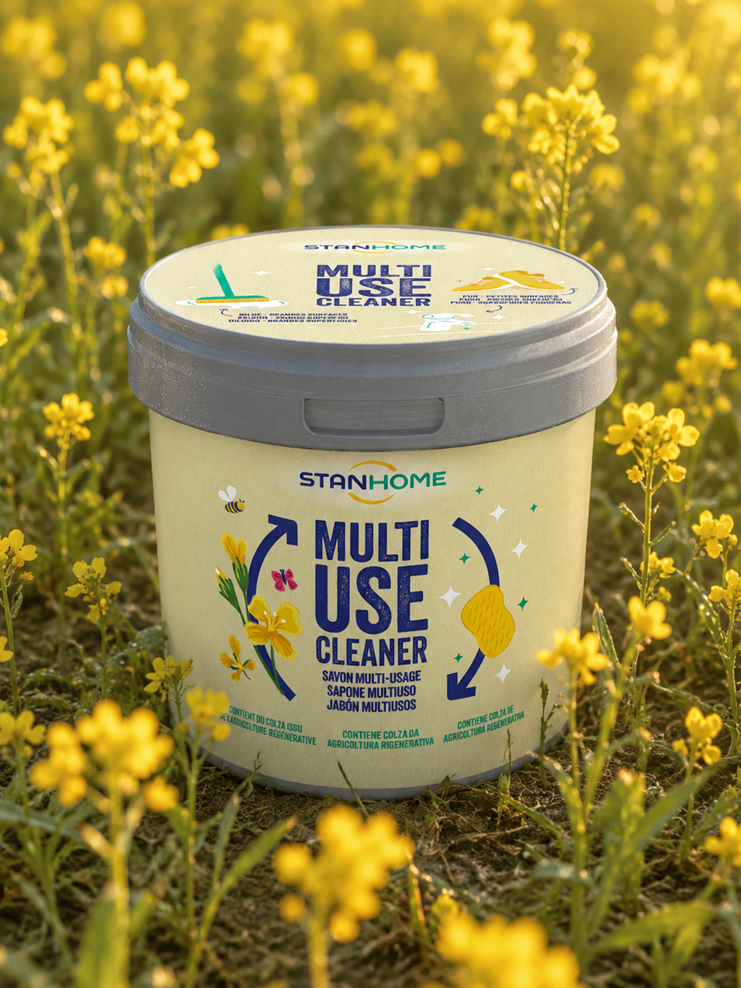 Pot de savon multi-usage Stanhome Multi Use Cleaner posé dans un champ de colza en fleur