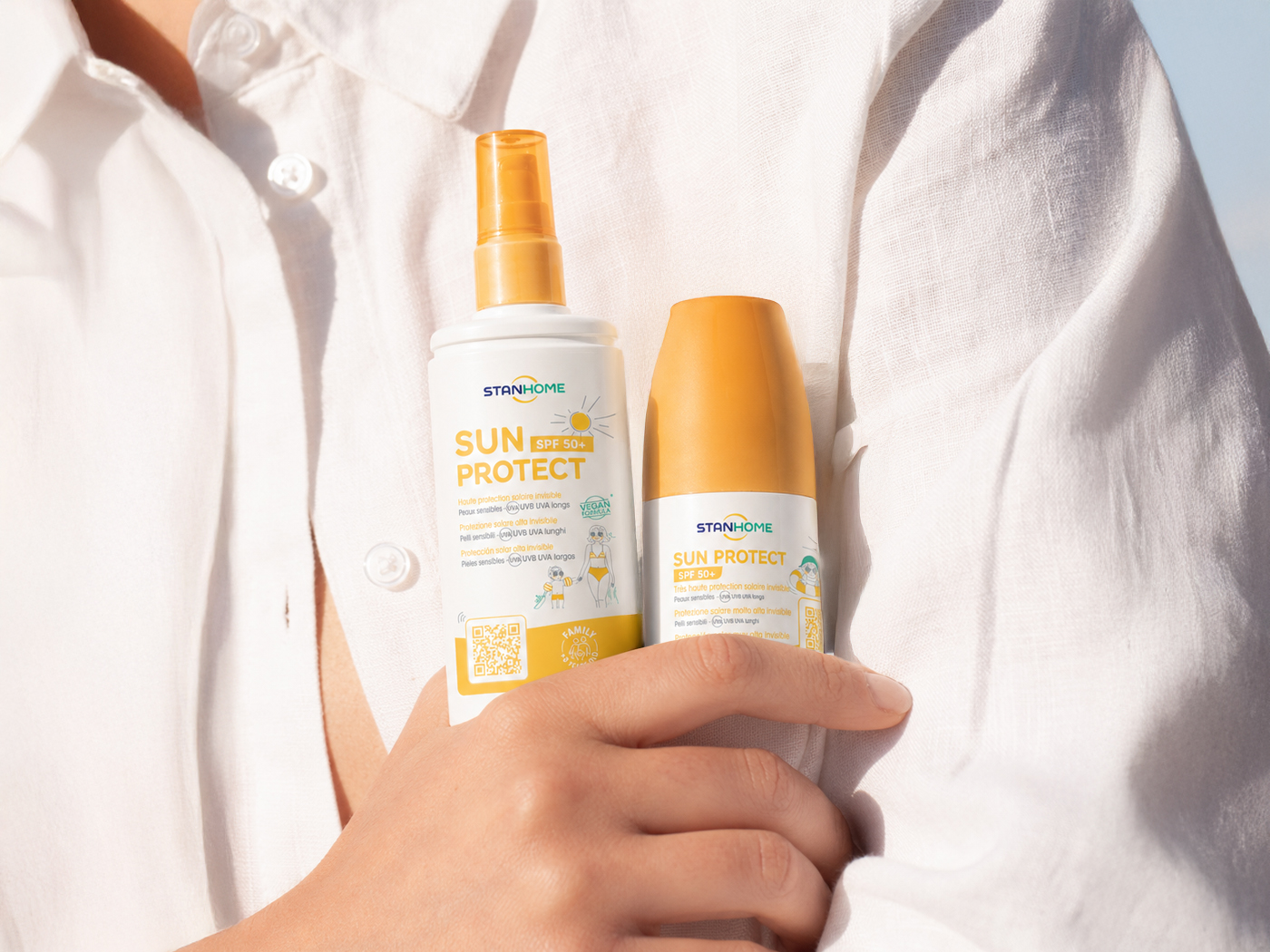 Spray et flacon Stanhome Sun Protect SPF 50+ tenus contre une chemise en lin